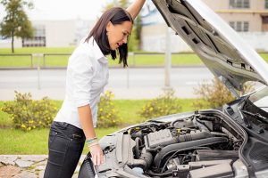 Woman looking at broken cars motor